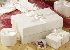 Large gift box with ribbon, ivory damask pattern. Other smaller boxes around it.