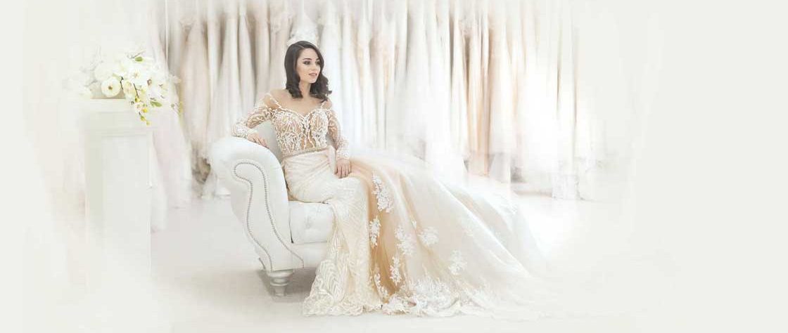 Bride in white dress sat on white chaise longue.